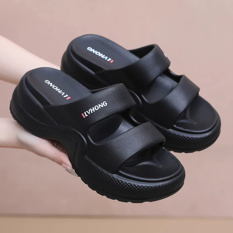 Sorte slip-on sandaler med dobbelte remme og kilehæl i hånden — Nordleva