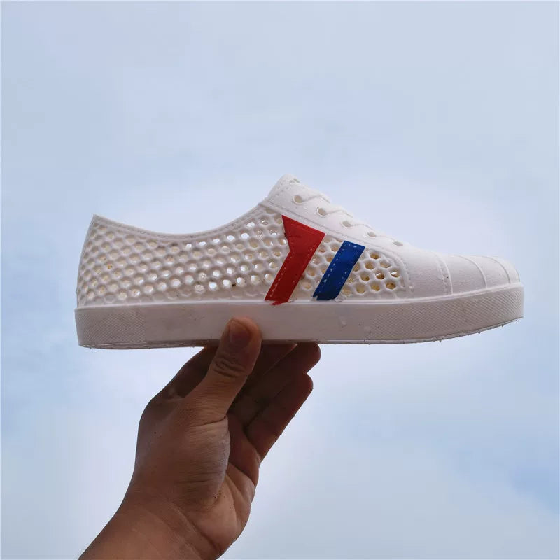 Hvid åndbar sneaker med perforeret overflade holdt i hånden — Nordleva